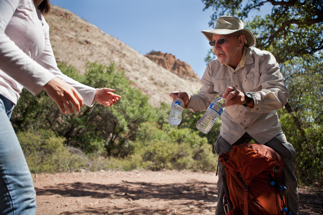 Jenn Slaiman, left, a Tucson Samaritans volunteer, received bottles of water from Robert Kee, right, while packing food and water supplies for migrants.