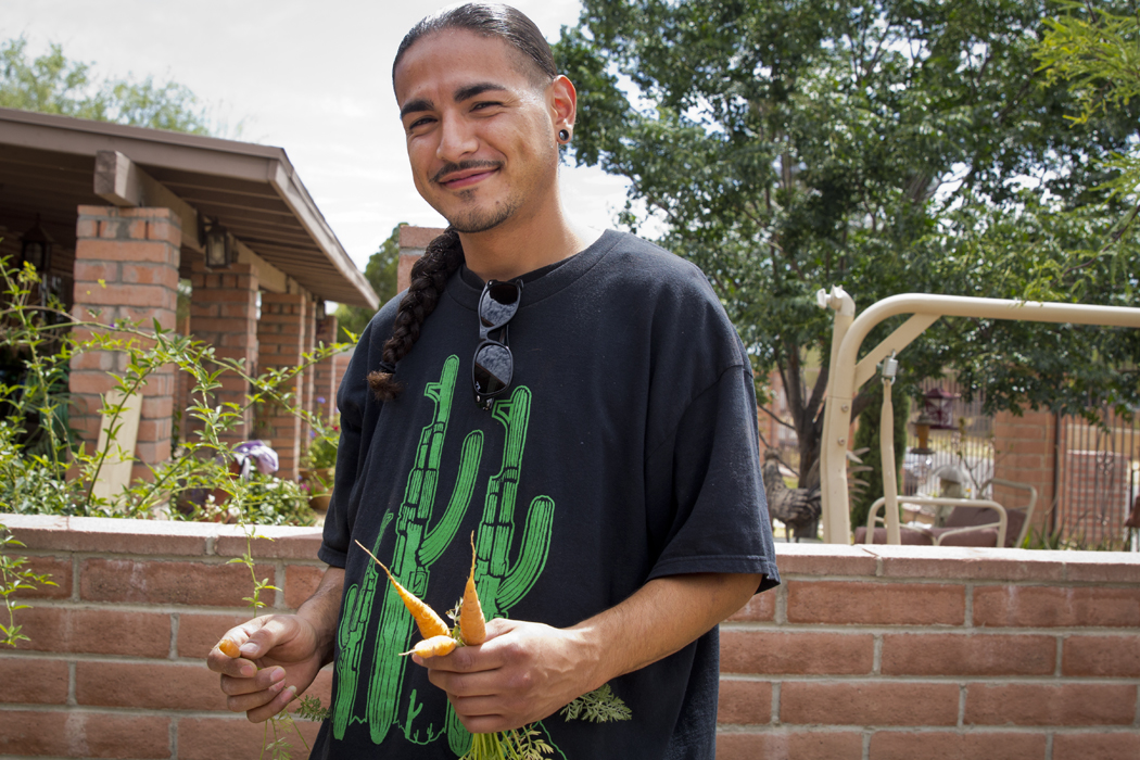 Jesus Romero, 26, a co-founder of Flowers and Bullets, with carrots that he grew in his yard.